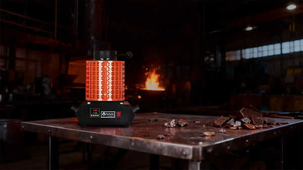 Industrial oven with glowing orange interior on a metal table in a workshop setting.